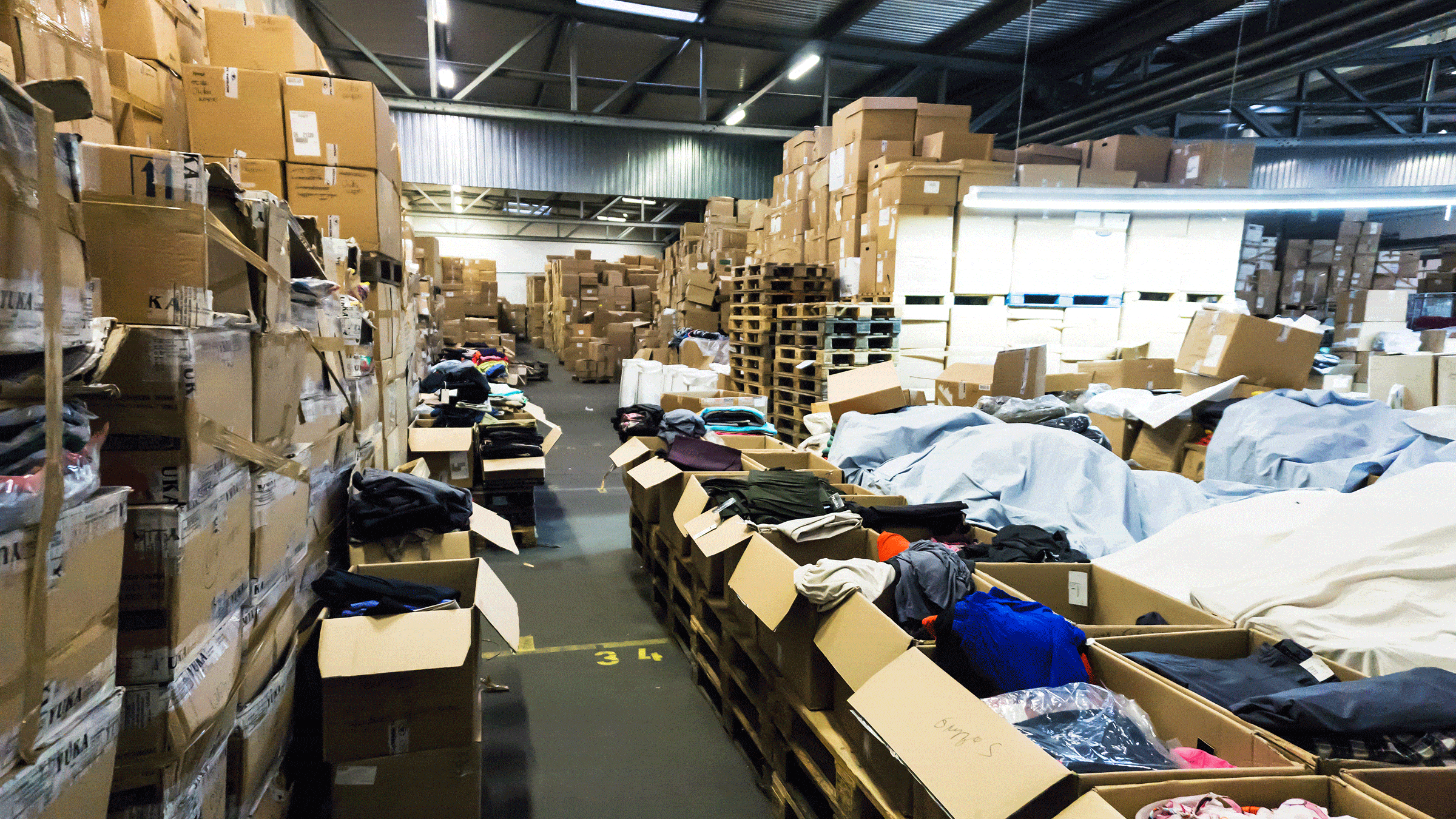 A warehouse containing boxes of clothes on shelves and on the floor