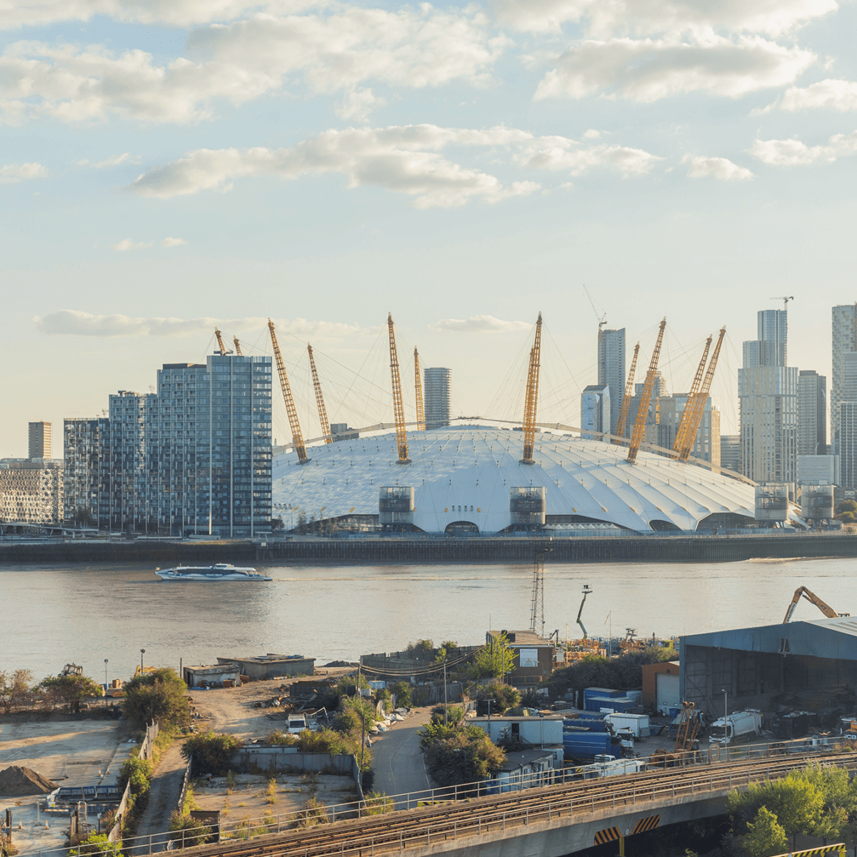 An photograph of the o2 arena in Greenwich, London, with the docklands skyline in the backgorund
