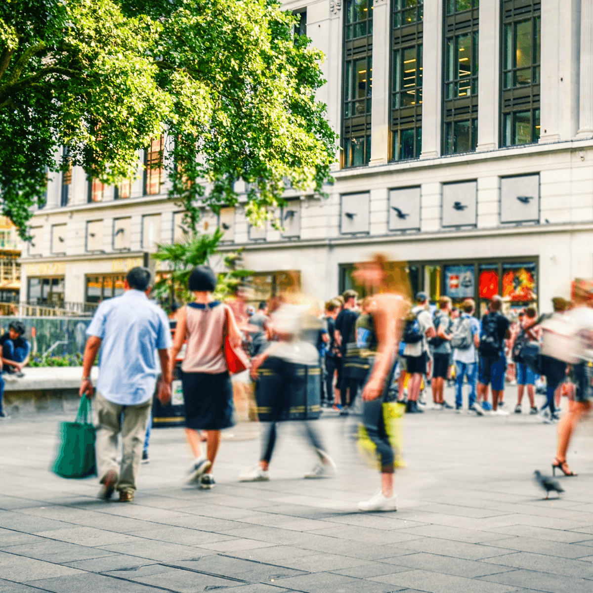 an image of a busy shopping square with shoppers carrying carrier bags walking by
