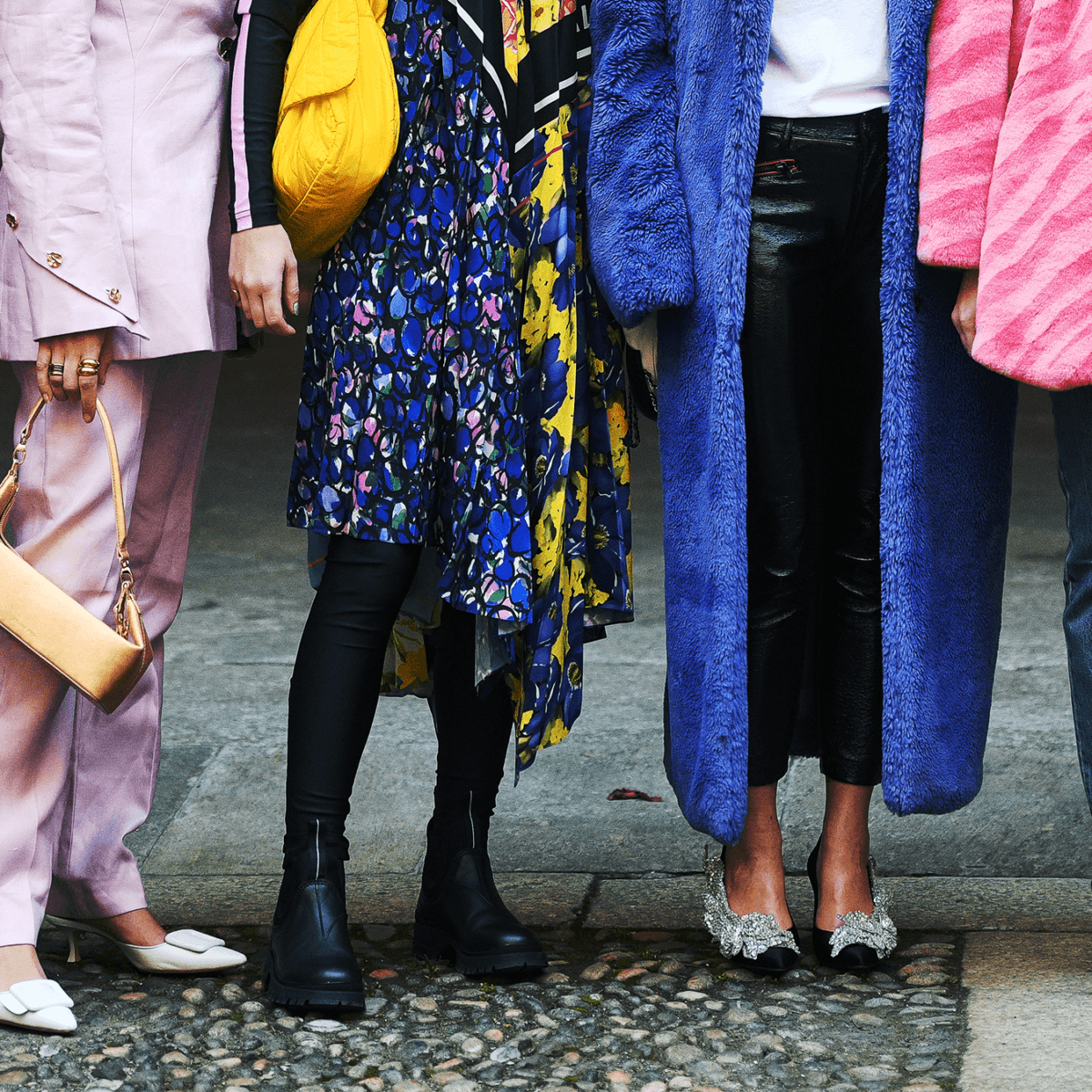 Five women dressed in colourful fashionable outfits stand in a row