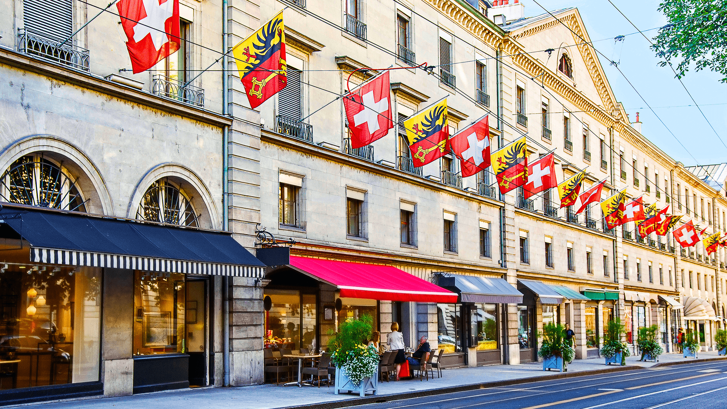 A high street in Geneva with Swiss flags hanging above shops.